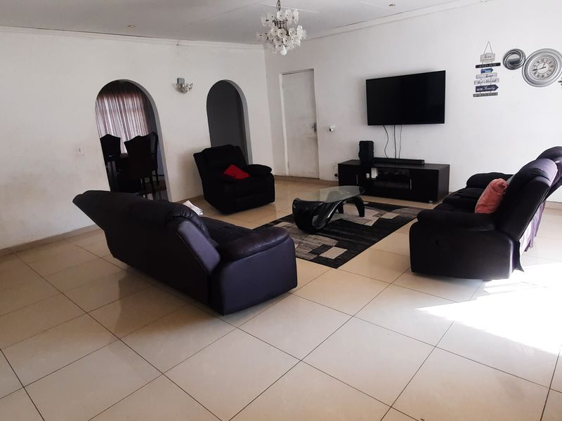 Spacious living room featuring large floor tiles, arched architectural details, and recessed lighting, providing a neutral foundation for modern interior design updates.