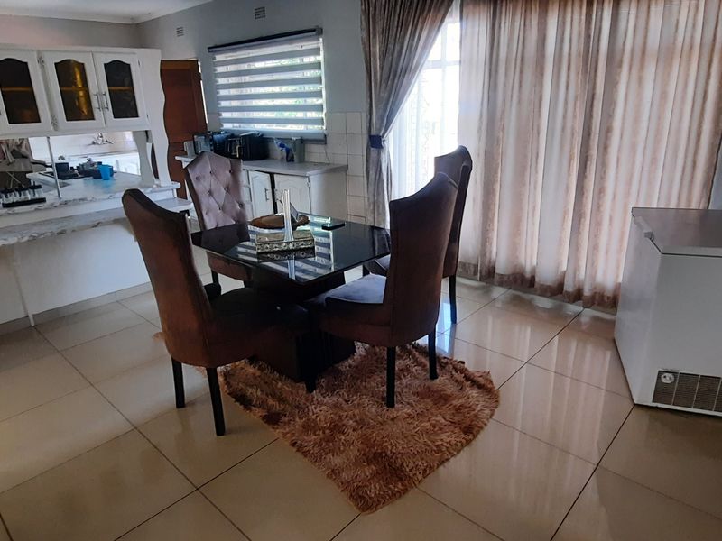 Open plan dining and kitchen area featuring tiled flooring, built-in cabinetry, and large windows with blinds, providing a functional living space.