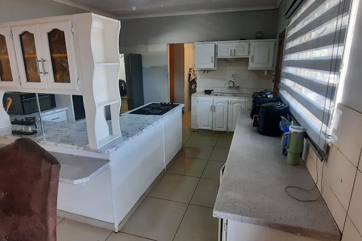 Functional kitchen featuring built-in cabinetry, laminate countertops, a built-in hob, and tiled flooring, offering a practical layout with potential for modern updates.