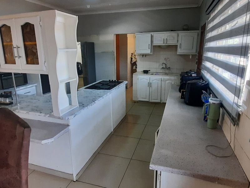 Functional kitchen featuring built-in cabinetry, laminate countertops, a built-in hob, and tiled flooring, offering a practical layout with potential for modern updates.