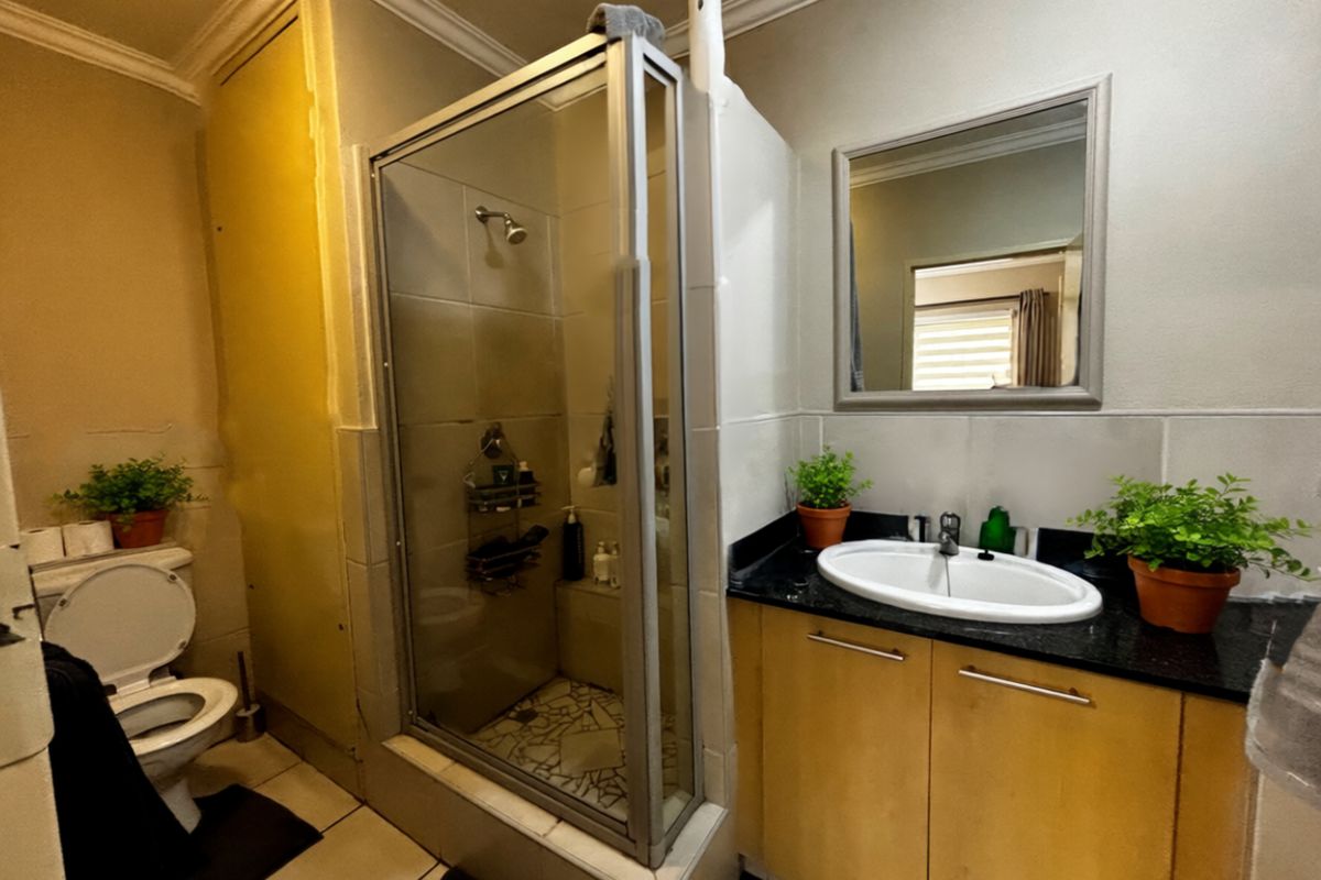 A functional bathroom featuring a glass-enclosed shower, a vanity with a granite countertop, and a standard toilet.