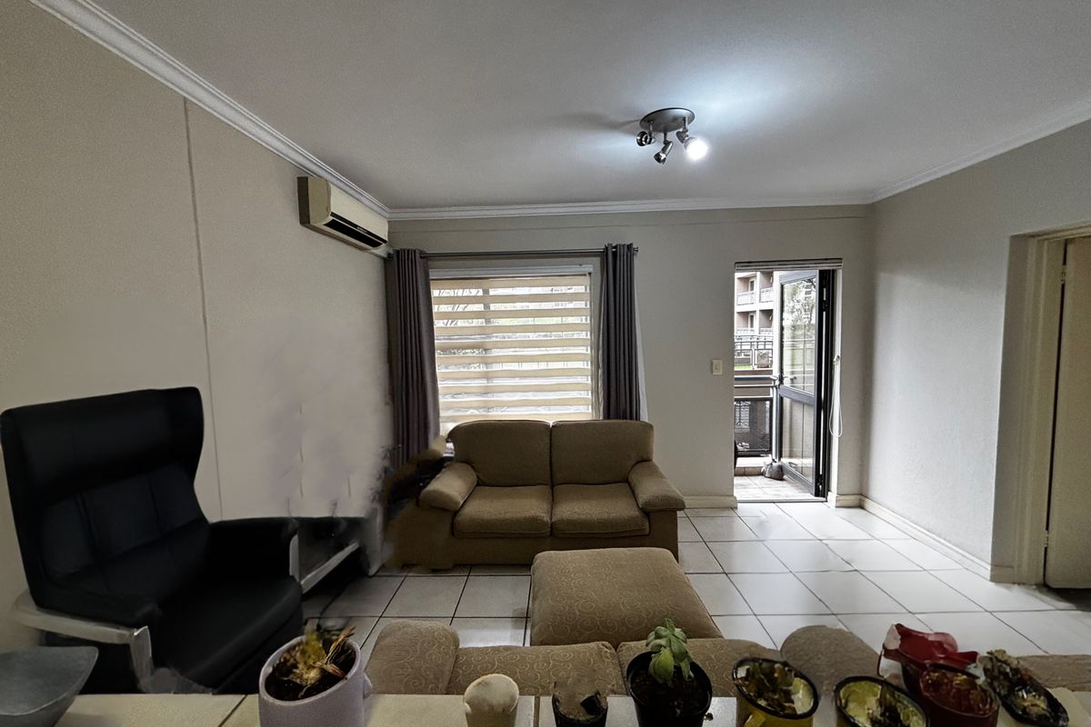 A living room featuring tiled flooring, crown molding, a wall-mounted air conditioning unit, and direct access to an outdoor balcony area.