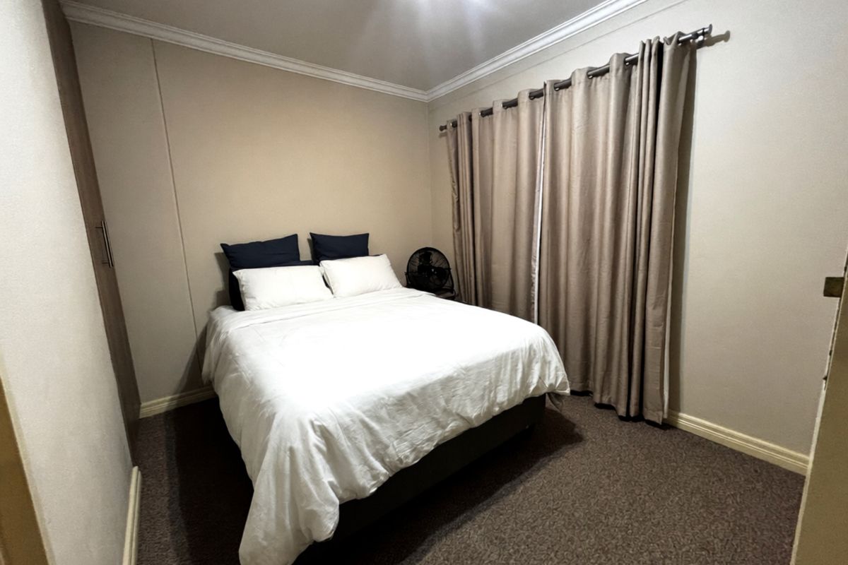 A standard bedroom featuring neutral wall tones, carpeted flooring, crown molding, and a built-in wardrobe.