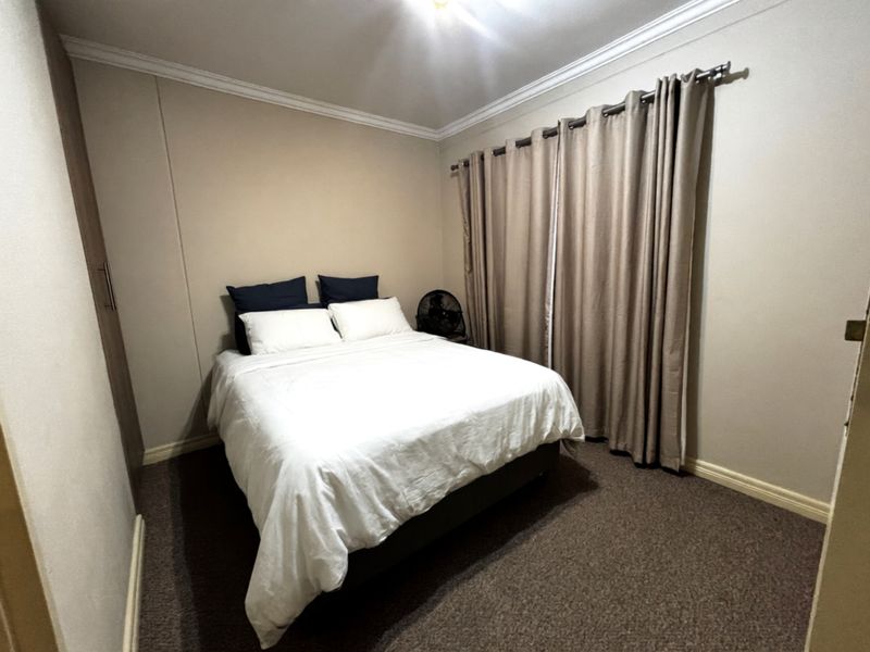 A standard bedroom featuring neutral wall tones, carpeted flooring, crown molding, and a built-in wardrobe.