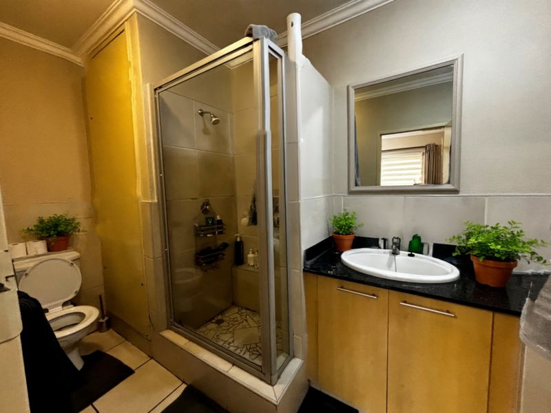 A functional bathroom featuring a glass-enclosed shower, a vanity with a granite countertop, and a standard toilet.