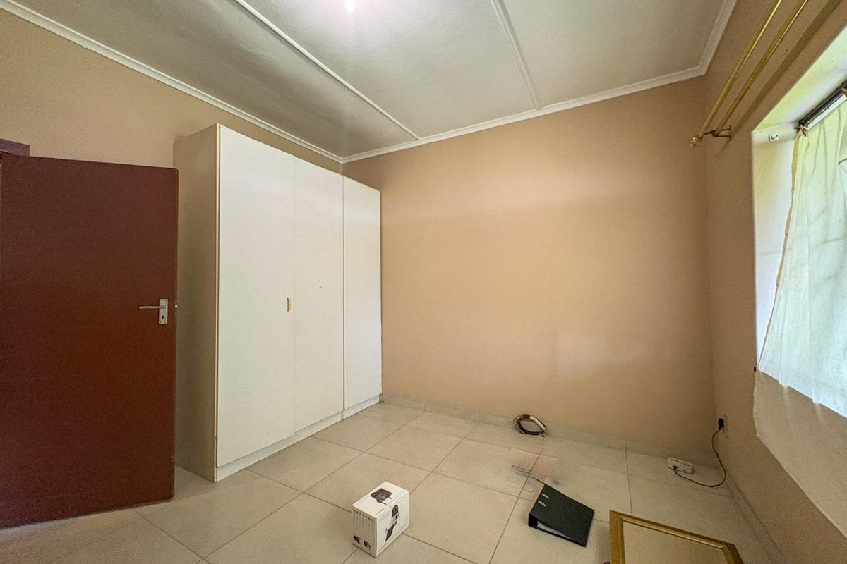 A bedroom featuring built-in white cabinetry, tiled flooring, and a standard door, offering a functional space ready for personalization.