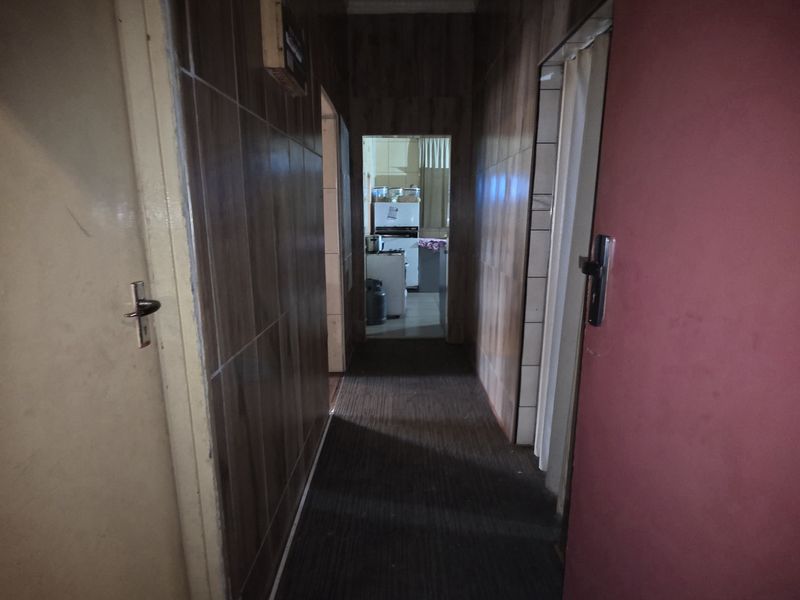 A narrow interior hallway featuring wood-look wall paneling and carpeted flooring, providing access to adjacent rooms within the home.