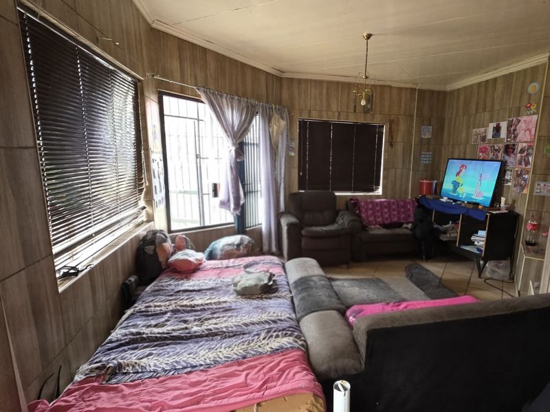 A living room featuring wood-look wall paneling, tiled flooring, and security bars on the windows.