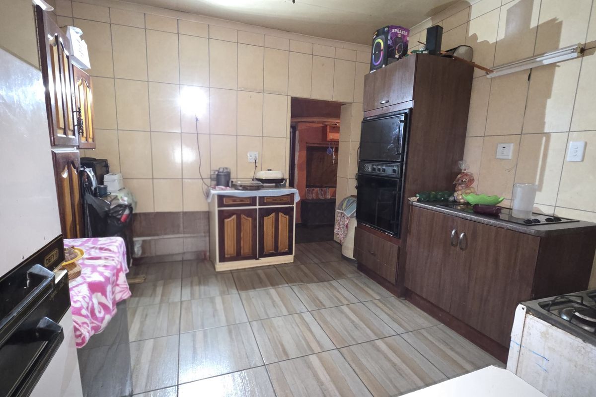 A functional kitchen featuring built-in cabinetry, a wall-mounted oven, and tiled flooring, offering a practical layout with potential for modernization.