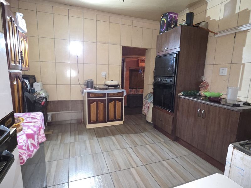 A functional kitchen featuring built-in cabinetry, a wall-mounted oven, and tiled flooring, offering a practical layout with potential for modernization.