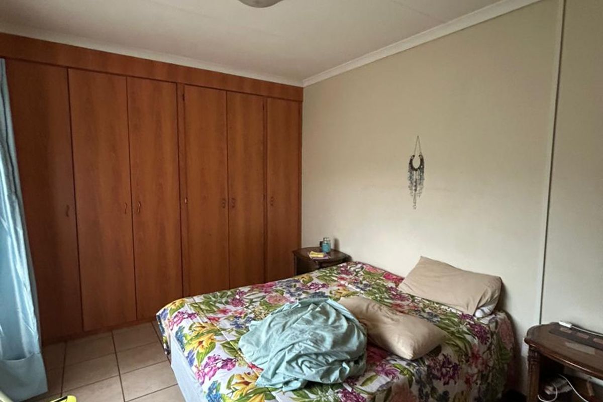 A bedroom featuring built-in wooden cupboards and tiled flooring.