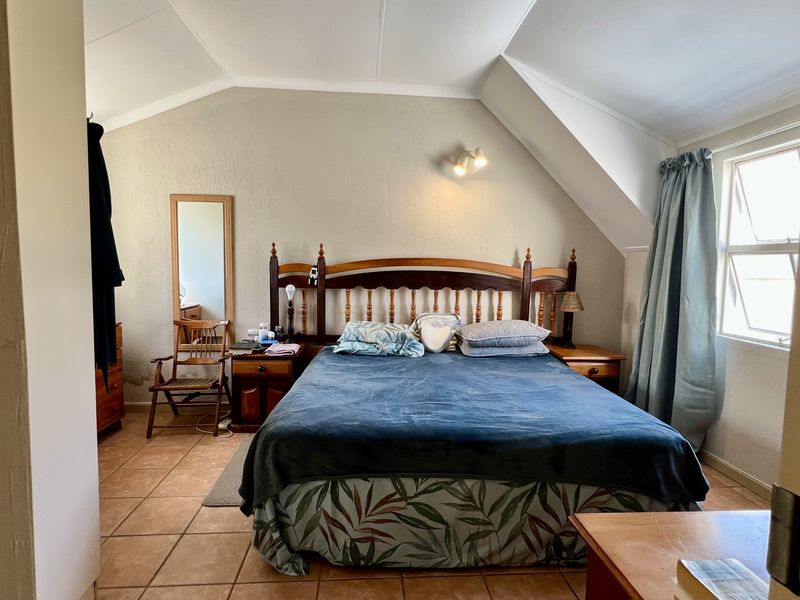 A bedroom featuring a pitched ceiling, tiled flooring, and a window with natural light.