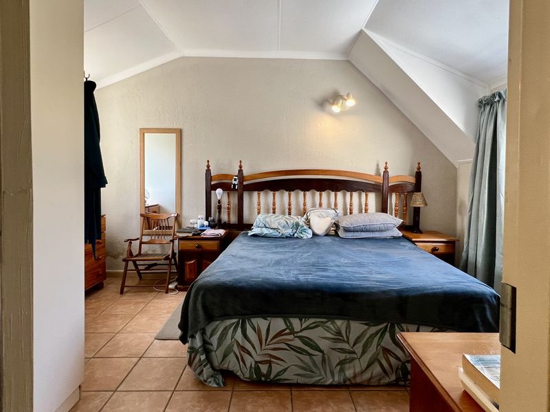 A bedroom featuring a vaulted ceiling, tiled flooring, and a built-in wall light fixture, viewed from the doorway.