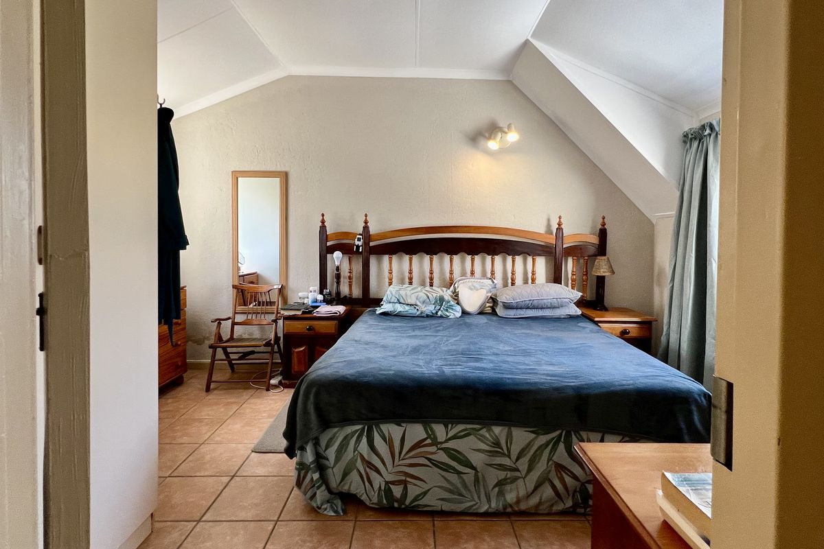 A bedroom featuring a vaulted ceiling, tiled flooring, and a built-in wall light fixture, viewed from the doorway.