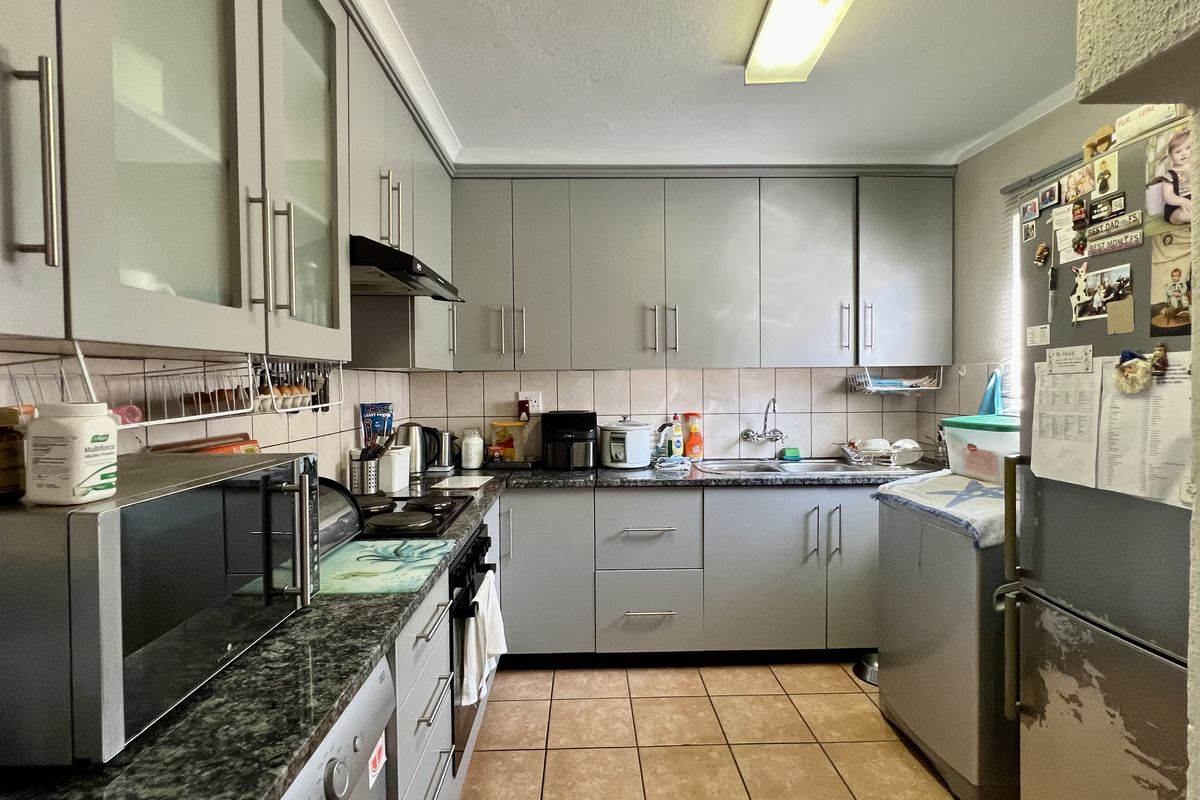 Functional kitchen featuring grey cabinetry, granite-look countertops, tiled backsplash, and integrated stove and extractor fan.
