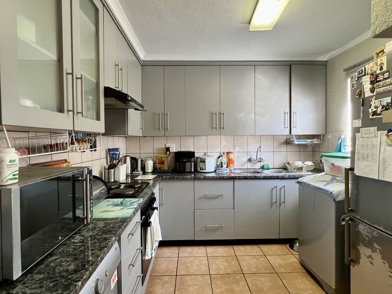 Functional kitchen featuring grey cabinetry, granite-look countertops, tiled backsplash, and integrated stove and extractor fan.