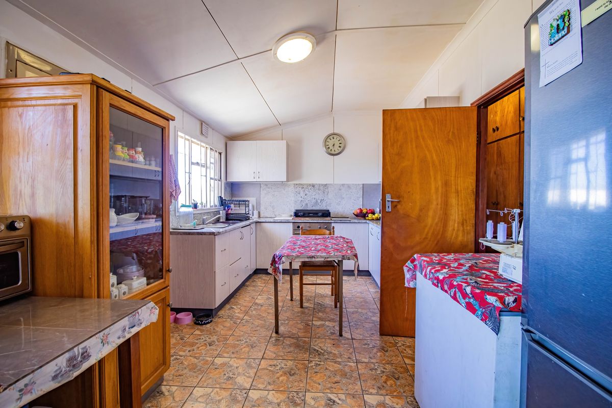 A dated kitchen featuring laminate cabinetry, tiled flooring, and a built-in stove, offering a functional layout with potential for modernization.