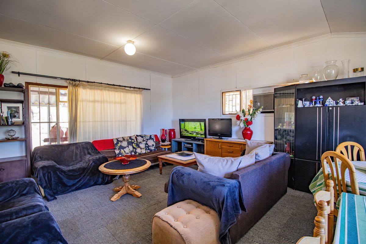 A spacious living room featuring carpeted flooring, large windows with natural light, and a functional layout suitable for comfortable family living.