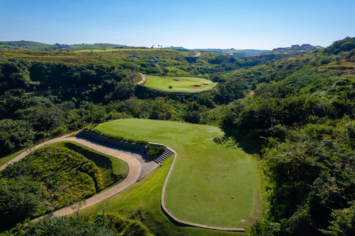 An elevated aerial view of a lush green golf course fairway and surrounding natural landscape within the estate.