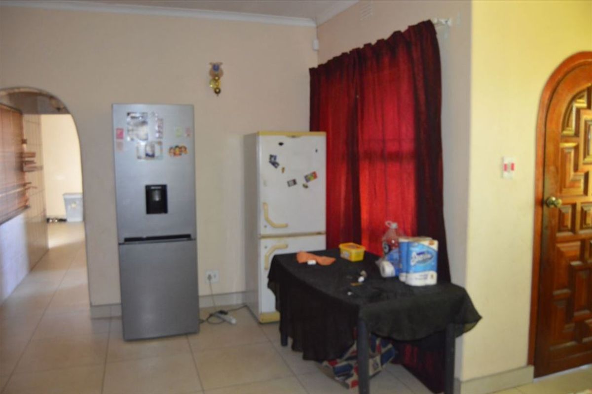 A view of a functional kitchen area featuring tiled flooring, an arched doorway, and a solid wood entrance door.