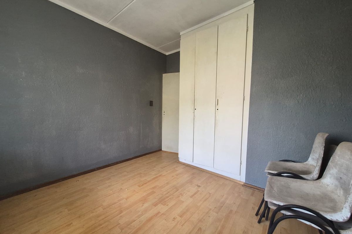 A bedroom featuring built-in cupboards, laminate flooring, and dark grey textured walls.