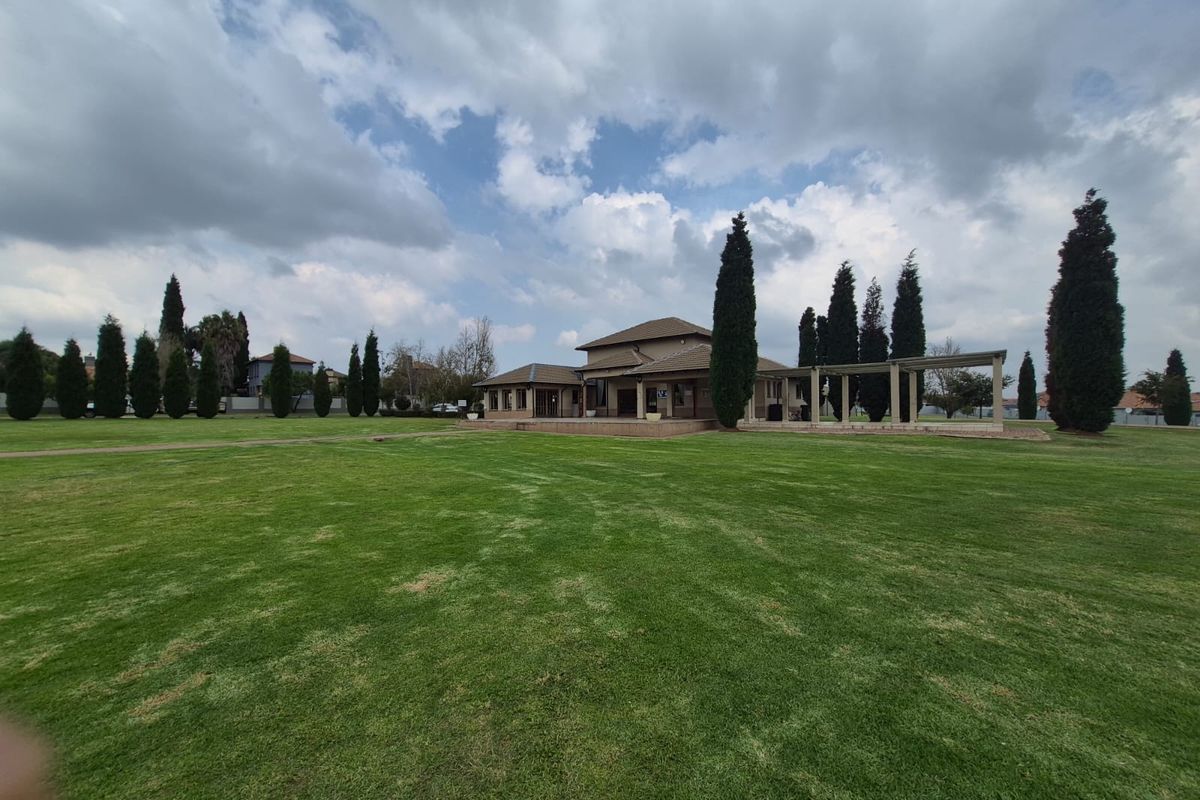 A spacious rear garden featuring a well-maintained lawn, a pergola, and a paved patio area extending from the main building structure.