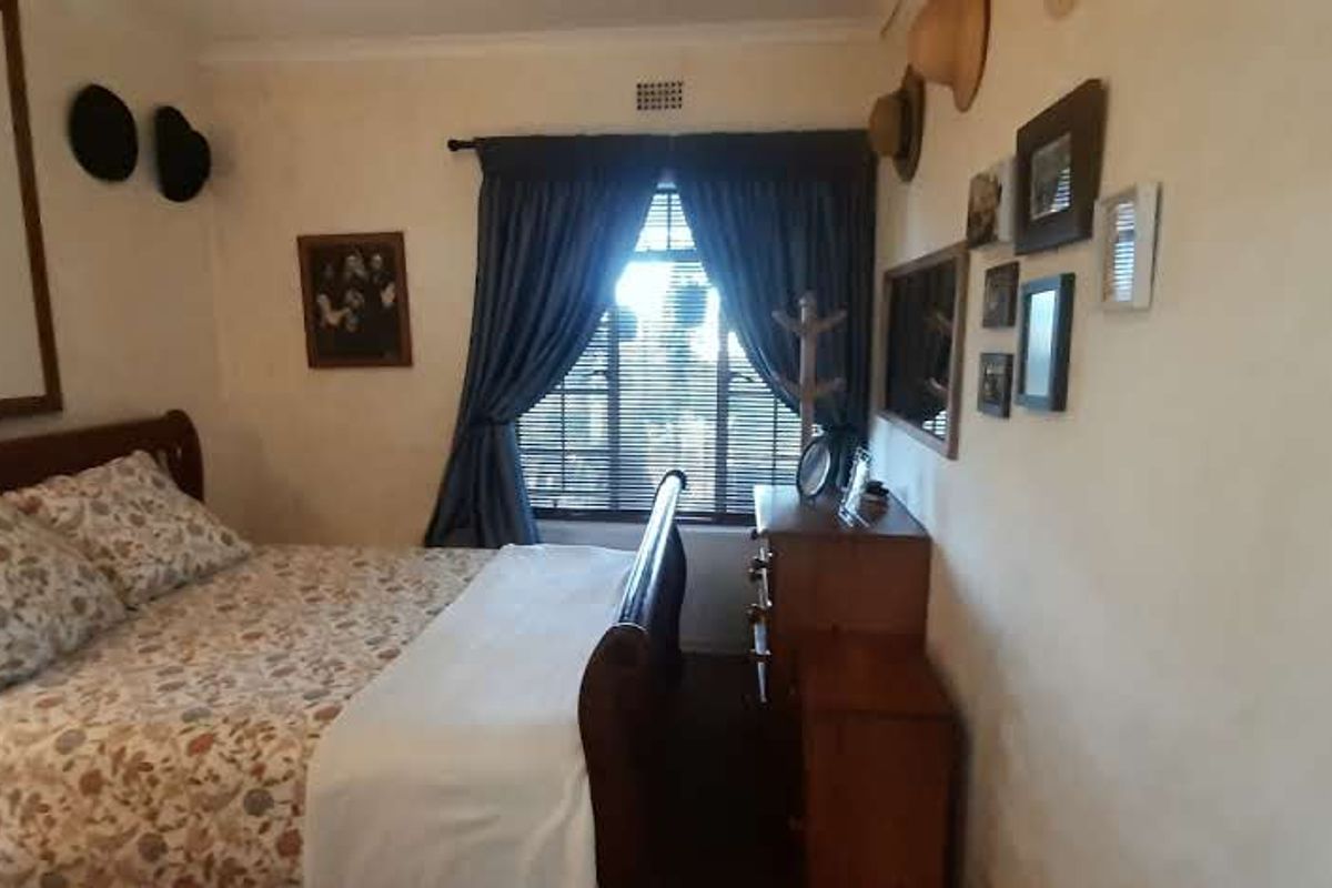 A cozy bedroom featuring a window with curtains and decorative cornice detailing.