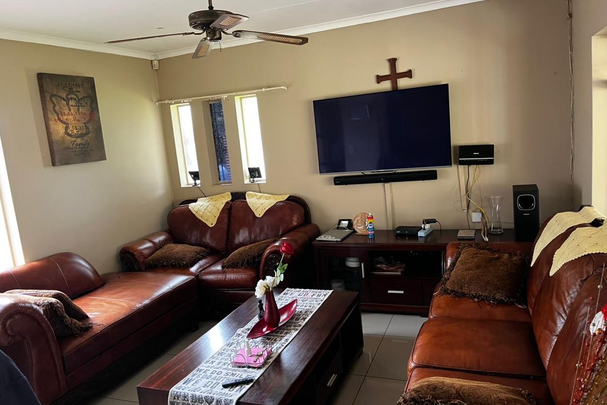 A comfortable living room featuring tiled flooring, a ceiling fan, and vertical windows, providing a functional space for relaxation.
