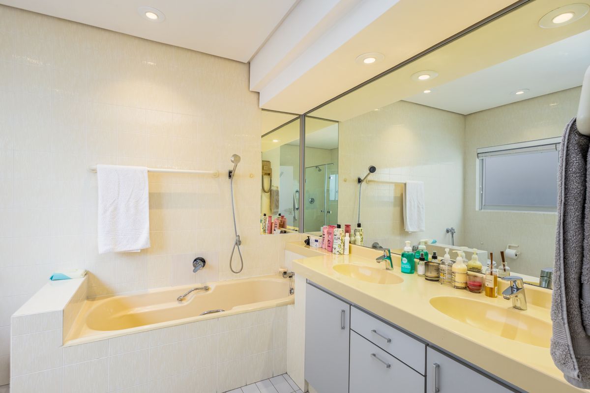A functional bathroom featuring a built-in bathtub, dual vanity sinks with integrated cabinetry, and a large wall-mounted mirror.