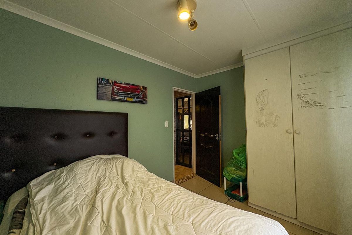 A bedroom featuring built-in wardrobe storage, tiled flooring, and a ceiling-mounted spotlight fixture, providing a functional space with potential for cosmetic updates.
