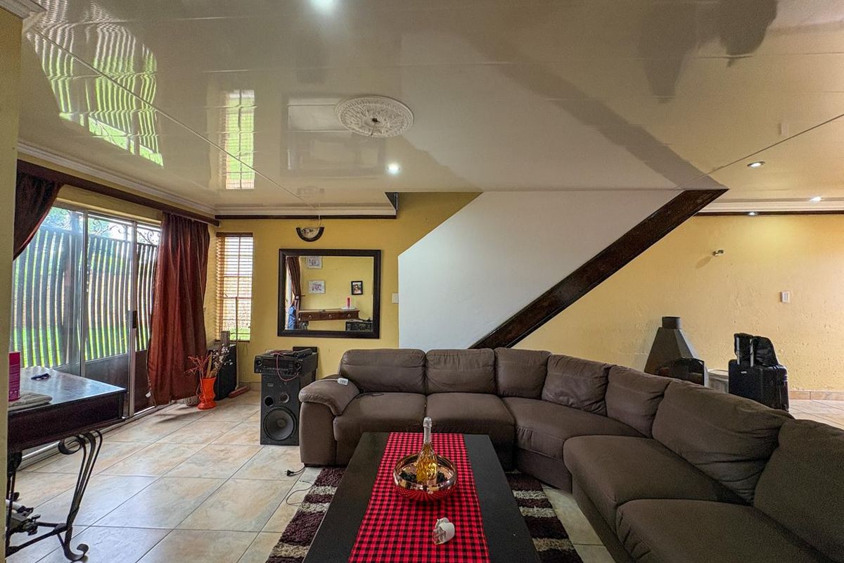 Spacious living room featuring tiled flooring, a built-in fireplace, and sliding glass doors providing access to the outdoor area.