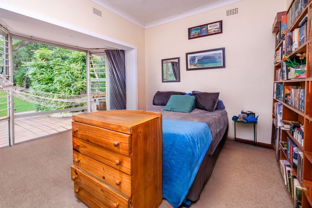 A bedroom featuring carpeted flooring, built-in shelving, and large sliding glass doors that open onto an outdoor patio area.