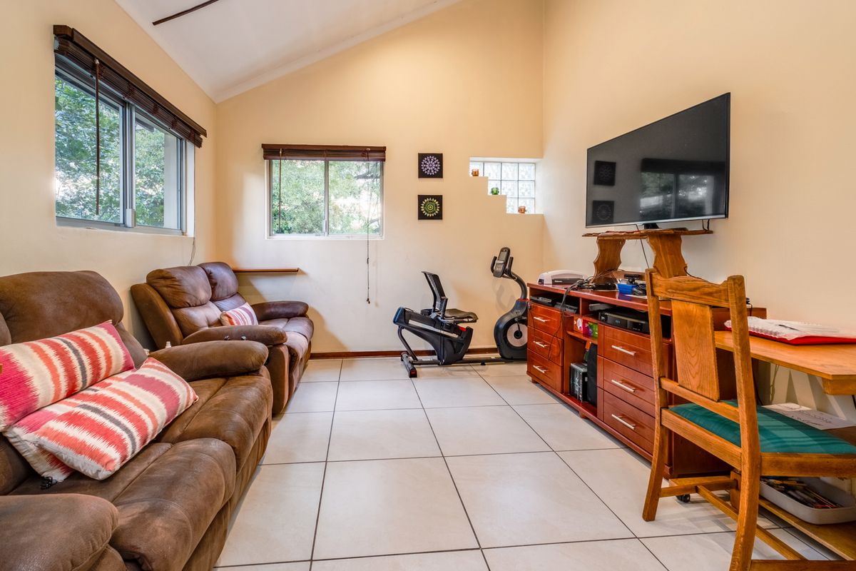 A functional living room featuring tiled flooring, vaulted ceilings, and large windows that provide natural light, suitable for a multi-purpose family space.