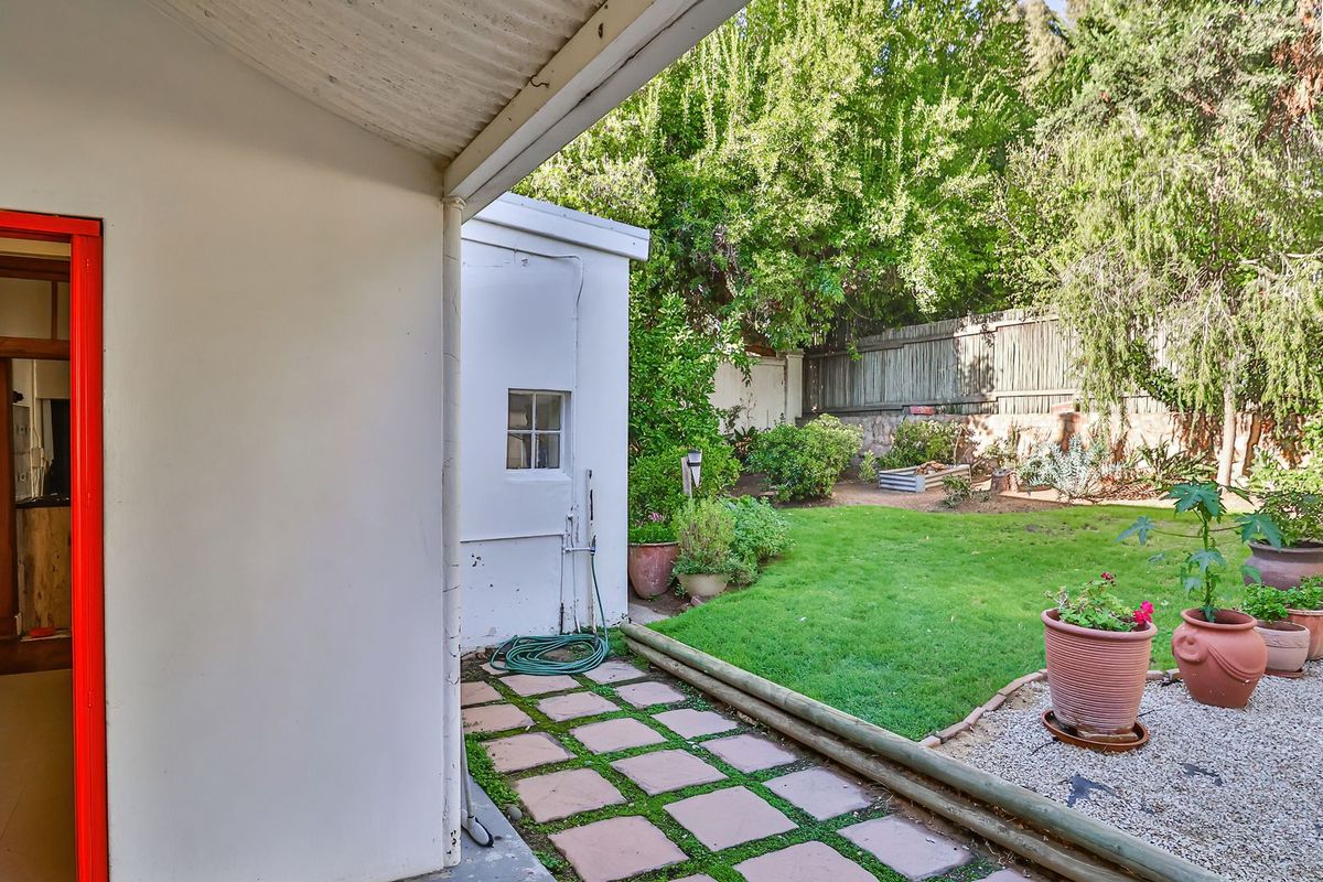 A rear garden area featuring a paved walkway, lawn, gravel section, and timber boundary fencing, providing a private outdoor space.