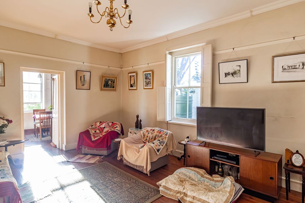A traditional living room featuring original timber flooring, picture rails, and classic sash windows with internal shutters, offering a character-filled space.