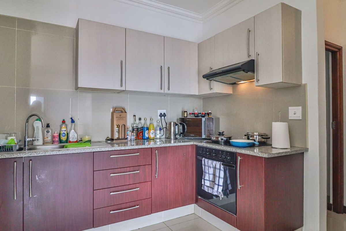 A functional kitchen featuring two-tone cabinetry, granite countertops, a built-in oven, and a stainless steel sink with a modern faucet.