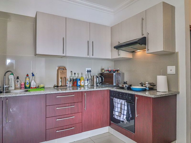 A functional kitchen featuring two-tone cabinetry, granite countertops, a built-in oven, and a stainless steel sink with a modern faucet.