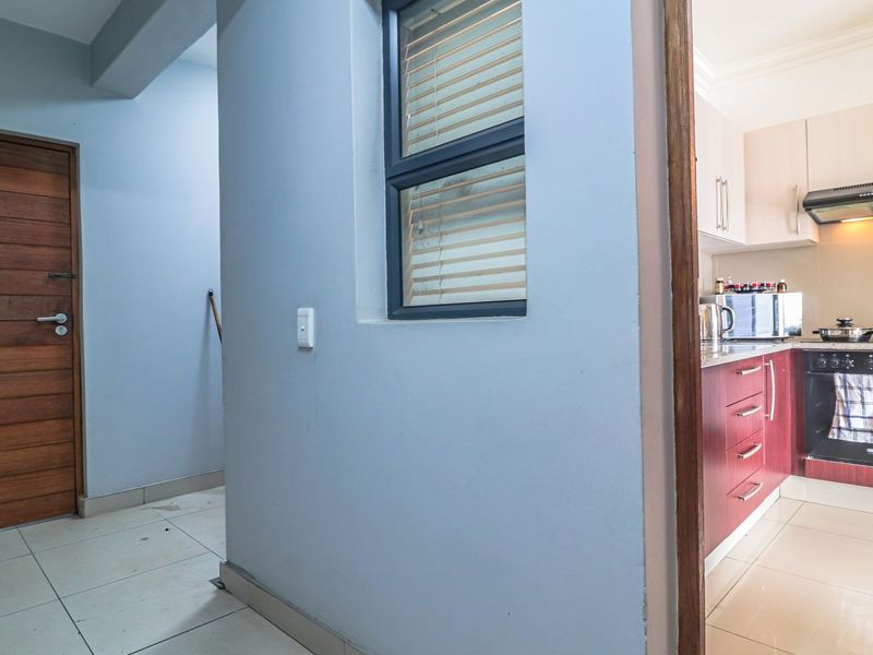 A view from a hallway into a compact kitchen featuring built-in cabinetry, a fitted oven, and an extractor fan.