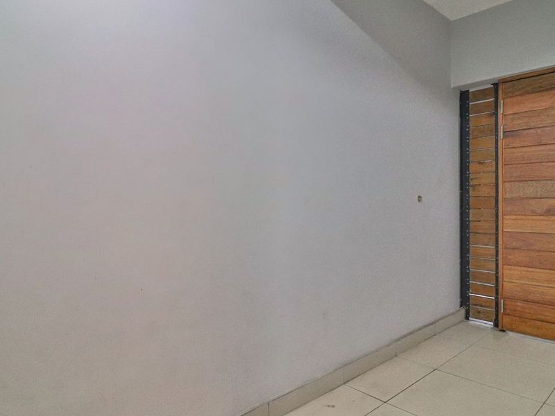 A simple entry area featuring tiled flooring and a solid timber door with a side security grille.
