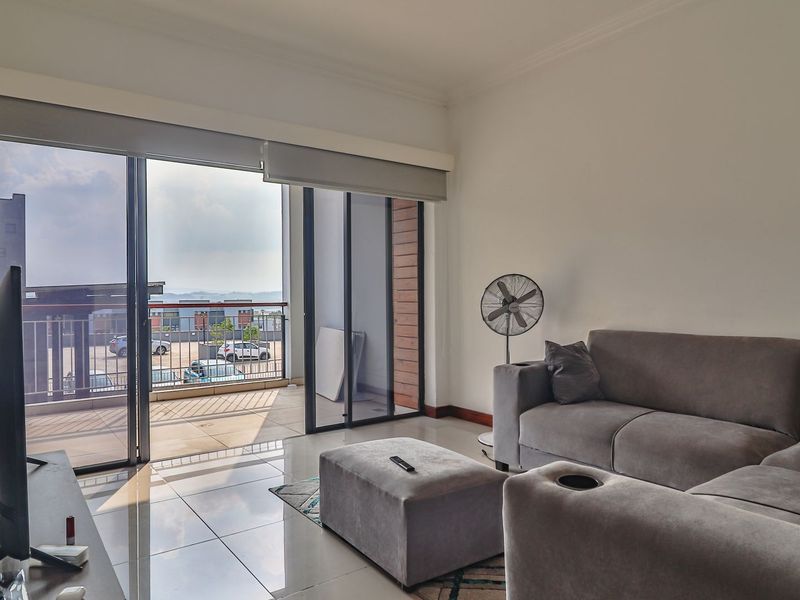 Bright living room featuring large sliding glass doors that open onto a private balcony, offering natural light and seamless indoor-outdoor flow.