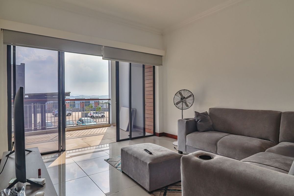 Bright living room featuring large sliding glass doors that open onto a private balcony, offering natural light and seamless indoor-outdoor flow.
