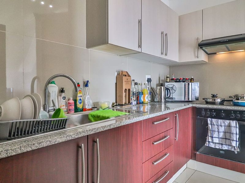 A functional kitchen featuring granite countertops, built-in cabinetry, a stainless steel sink, and integrated oven with extractor fan.