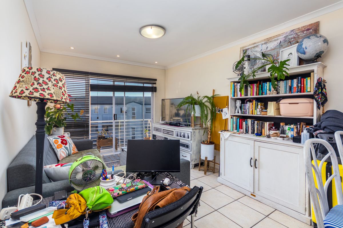 A living room featuring tiled flooring, a sliding glass door leading to a balcony, and built-in ceiling lighting.