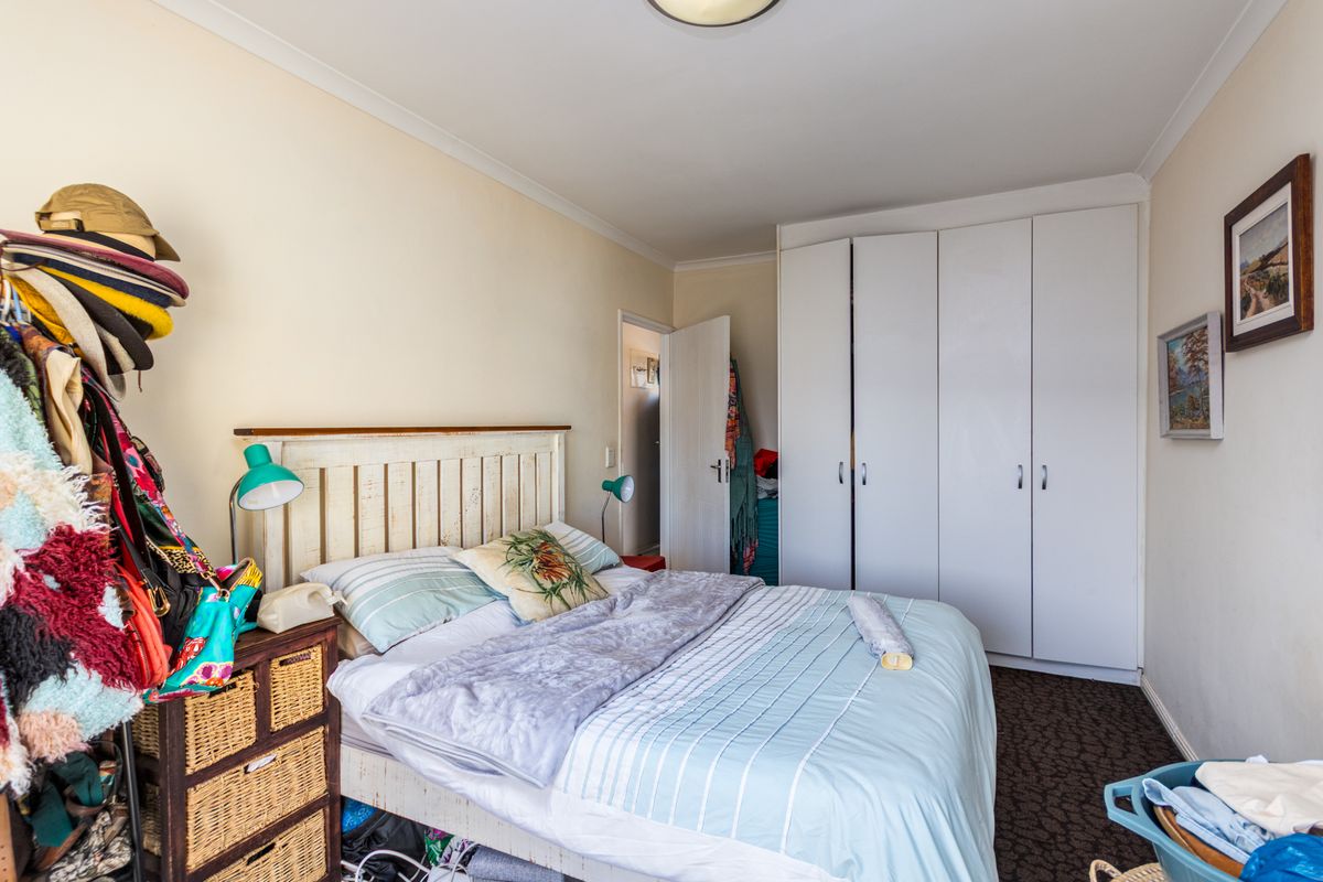 A bedroom featuring built-in white wardrobes and patterned carpeting, providing functional storage space within the apartment.
