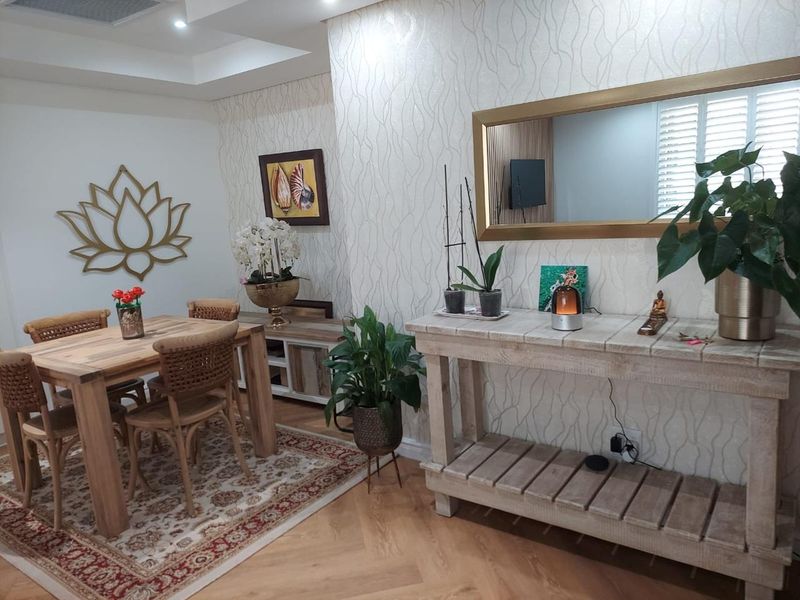 A well-maintained dining area featuring herringbone timber flooring, recessed ceiling lighting, and decorative wallpaper.