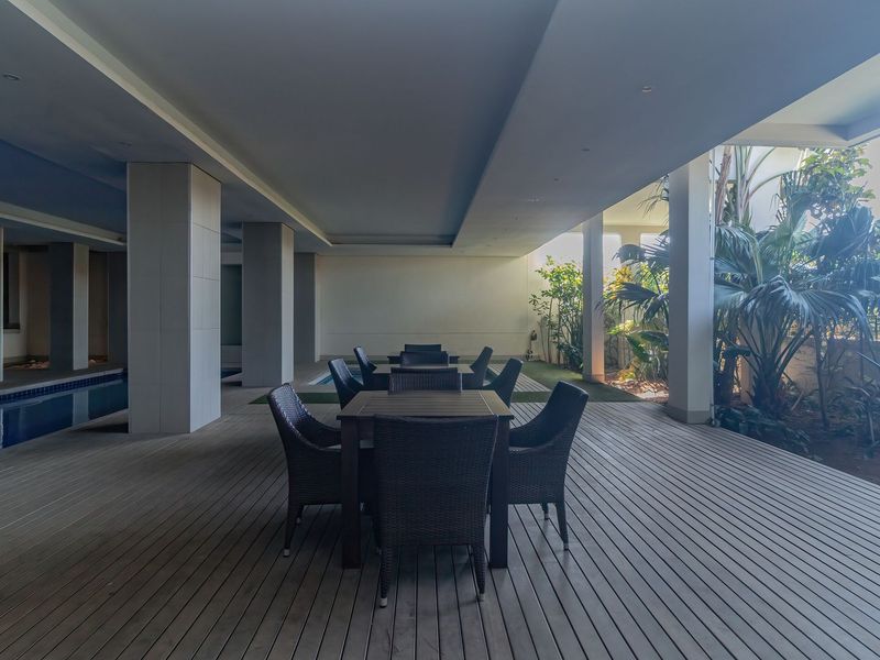 Spacious covered patio featuring timber decking, recessed lighting, and direct access to an adjacent swimming pool area.