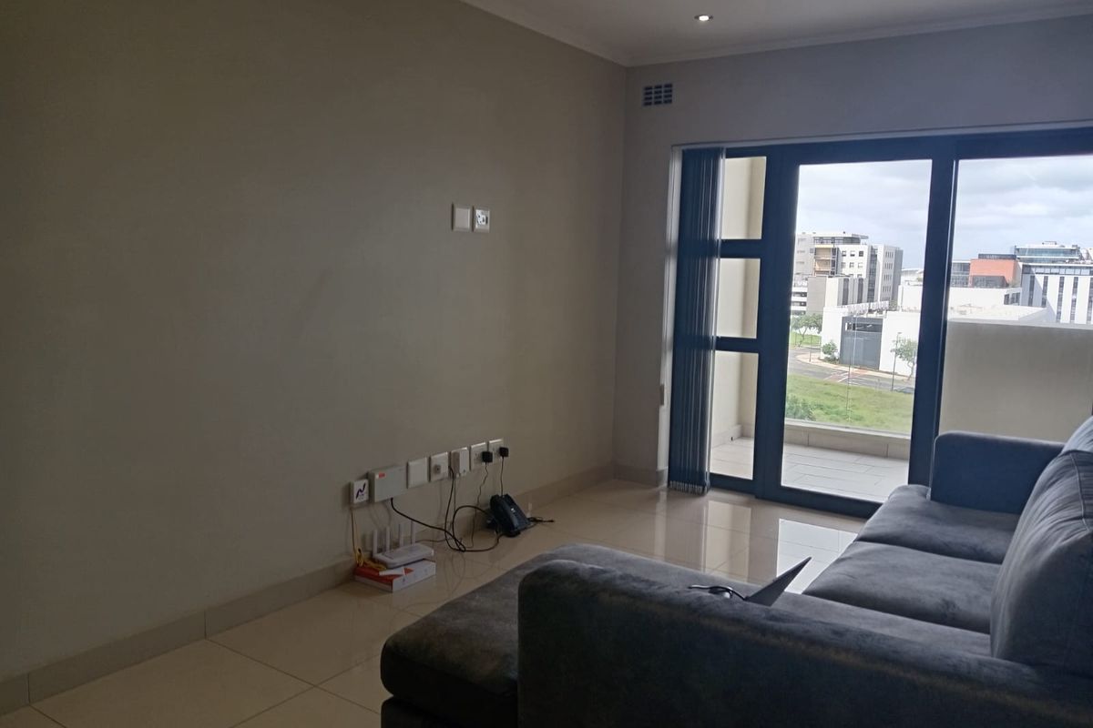 A living room featuring large glass sliding doors leading to a balcony, tiled flooring, and recessed ceiling lighting.