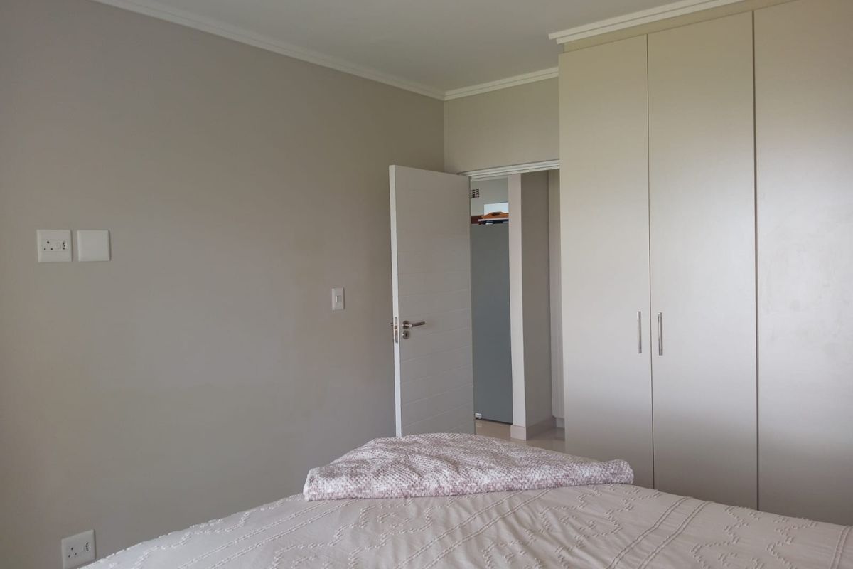 A bedroom featuring neutral wall tones, built-in floor-to-ceiling cabinetry, and a doorway leading to an adjacent space.