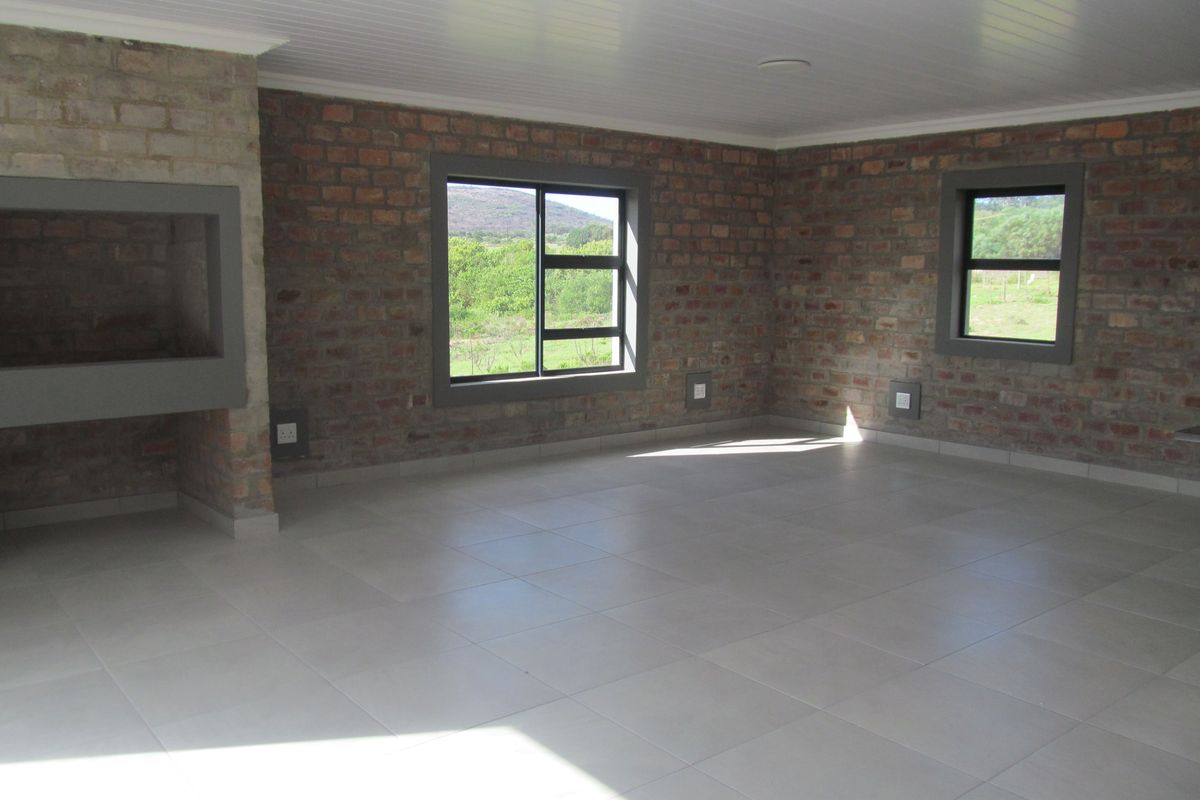 Spacious living area featuring exposed brick walls, large windows with scenic views, tiled flooring, and a built-in fireplace.
