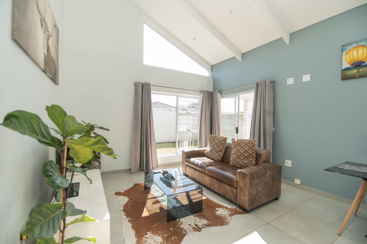 Bright living room featuring high vaulted ceilings, large windows, and sliding glass doors that provide ample natural light and access to the outdoor area.